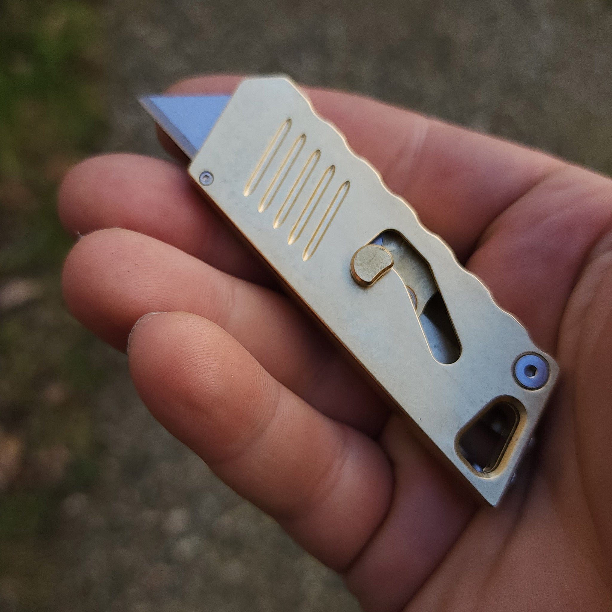 focusworks bob the boxcutter in brass held in a hand