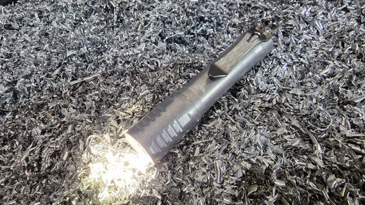 FocusWorks EDC Flashlight sitting in bed on titanium metal